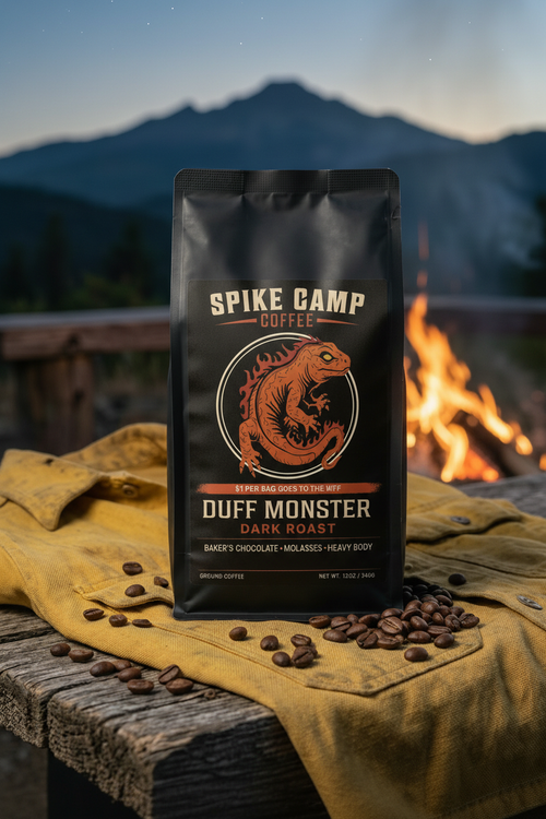 Spike Camp Duff Monster coffee bag with coffee beans on a wooden surface with a mountain backdrop